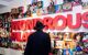 Man in coat looking at a wall of memoraibilia, photos of famous Liverpudlians