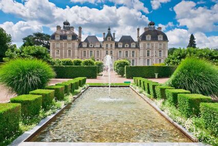 Front of the chateau with a beautiful garden, pond and fountain in the foreground