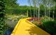 A yellow brick walking path/ bridge running across a small river in the Chaumont gardens