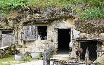 A view of the entrance to a troglodyte site. There is old wood being used as the framing for the doors and windows.