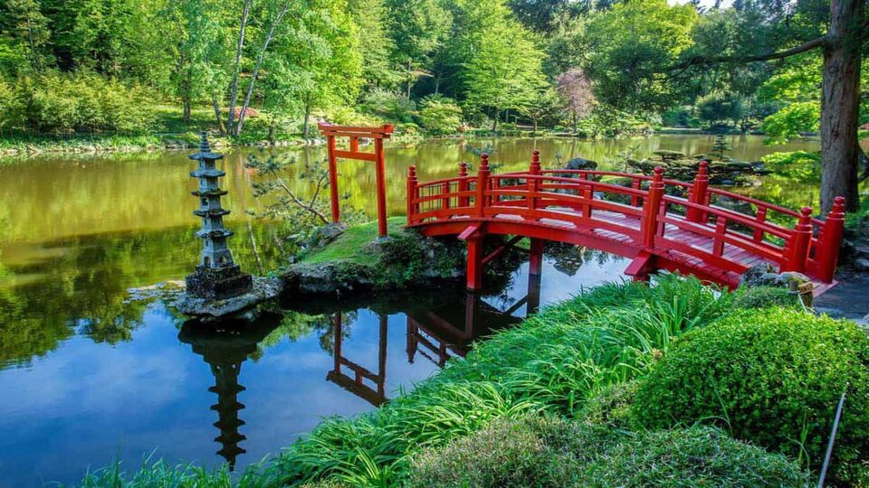 Red bridge crossing pond in garden