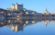 Saumur castle and Saint Peter's church being reflected on the Loire river during a blue summer's day
