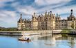 Rear side of Chambord Chateau with a small boat passing on the river in front of it