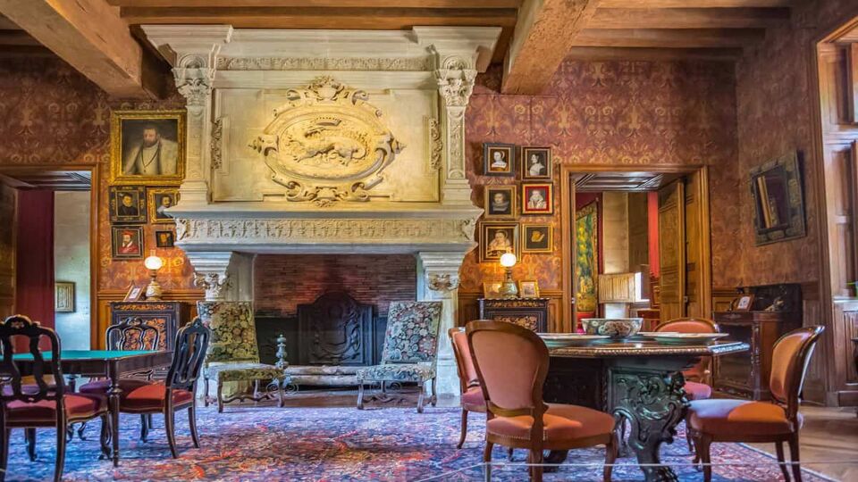 Interior old-fashioned lounge of the chateau with large stone fireplace