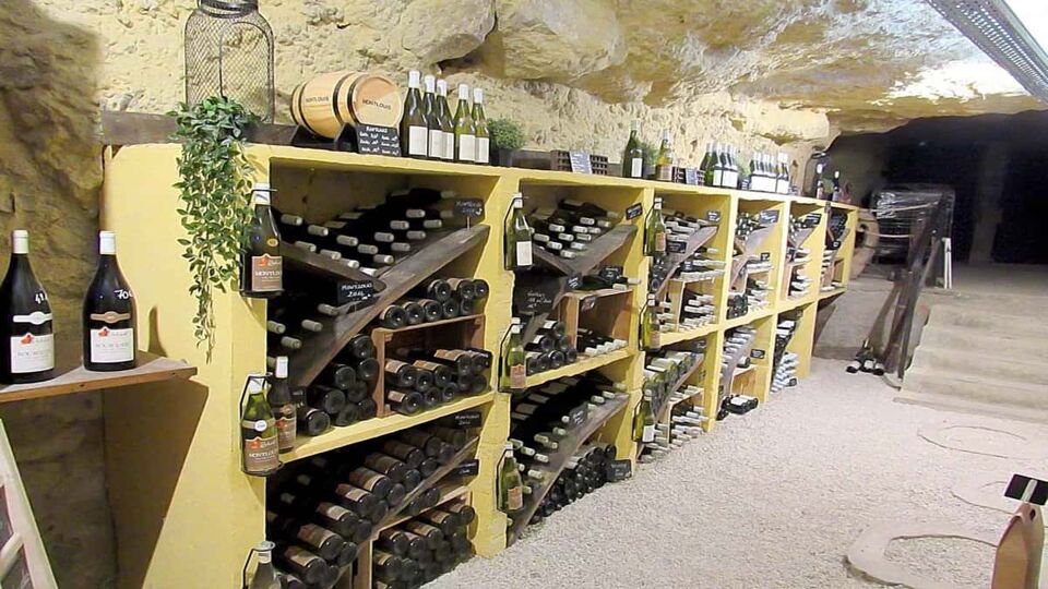 Inside a cellar, with bottles of Vouvray stacked in shelves against the wall