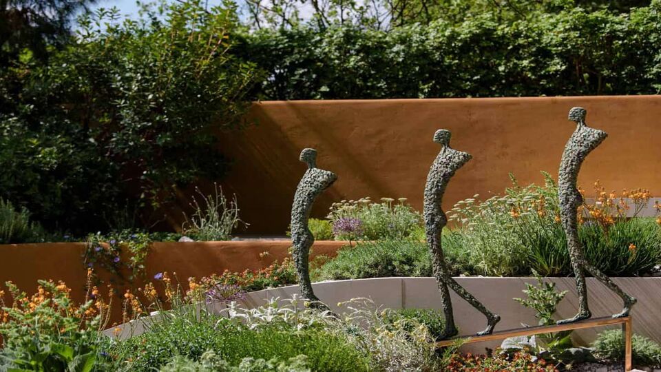 View of a small garden with 3 stick men statues sticking out of flowers