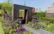 A contemporary garden with purple flowers and a large bronze square arch