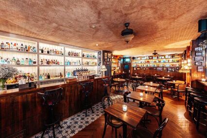 A beautiful underground wooden bar with a lighted bar full of gin bottles