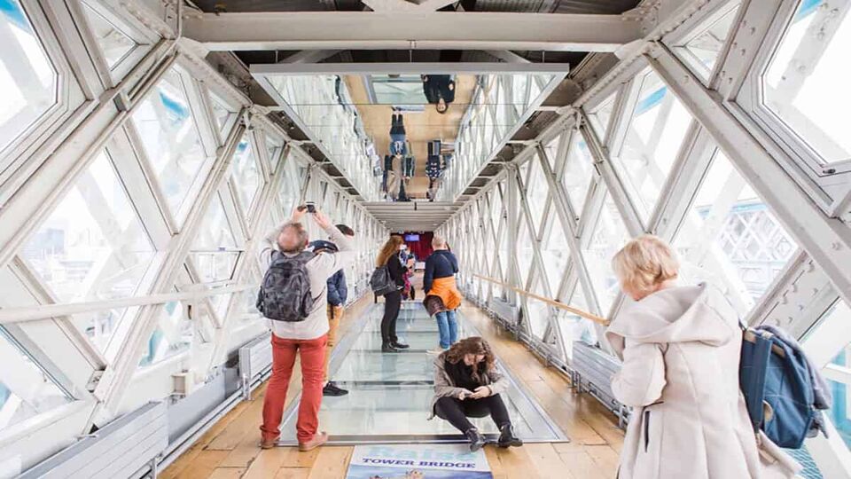 tourists walking over the glass-floored walkway in tower bridge