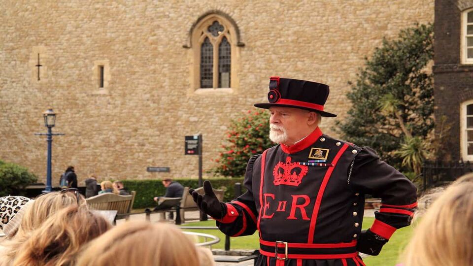 A Yeoman Warder leads visitors on a tour through the Tower during the day
