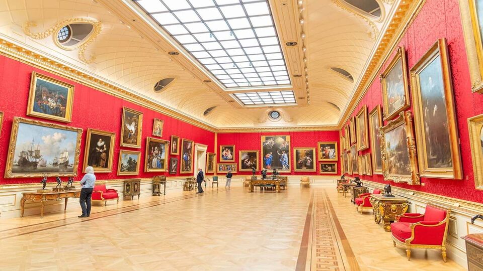 Interior of the Wallace Collection art gallery, with bright red walls covered in gold-framed paintings