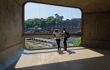 Two tourists looking through a window in the museum out to the amphitheater