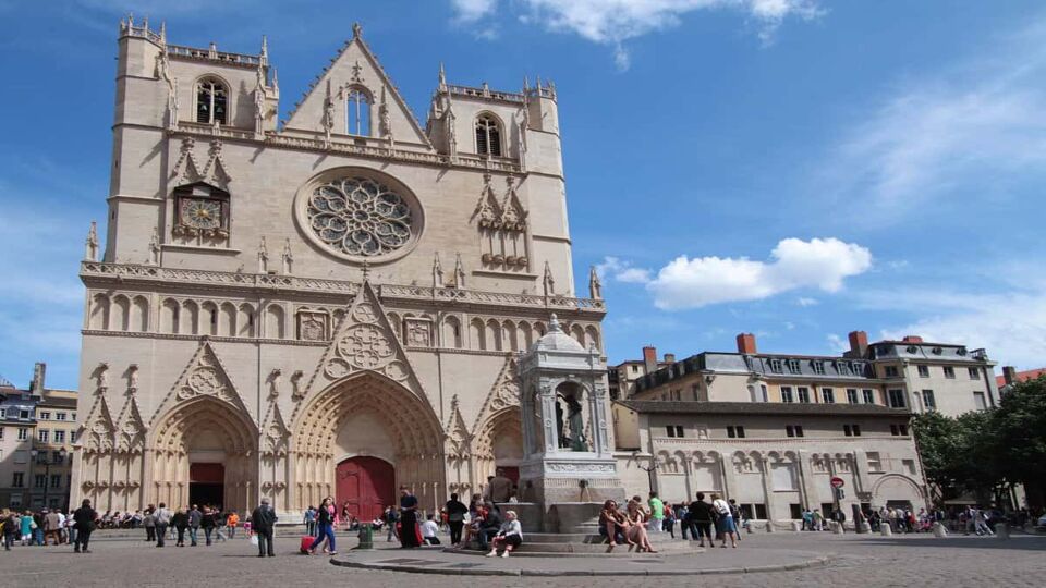 Tourists on Place Saint-Jean, with exterior front facade of the cathedral behind
