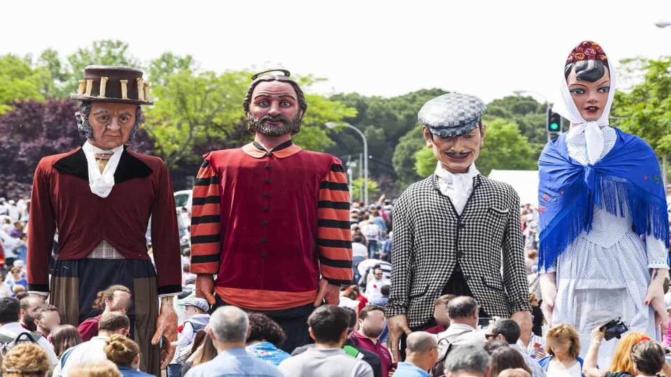 Four large effigies stand tall over a crowd of festivalgoers.