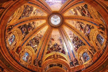 The ceiling of the Royal Basilica of St Francis the Great. The ceiling is domed with yellow-golden moulding and painted frescoes.