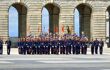 The changing of the guard ceremony at the Royal Palace of Madrid. Guards wearing blue uniforms, white gloves, blue hats line up holding flags.