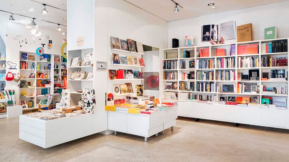 The gift shop of the Thyssen-Bornemisza Museum. Books and souvenirs are displayed on white shelves.