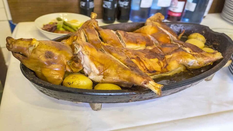 Roasted Suckling Pig of Botin displayed with cooked new potatoes.