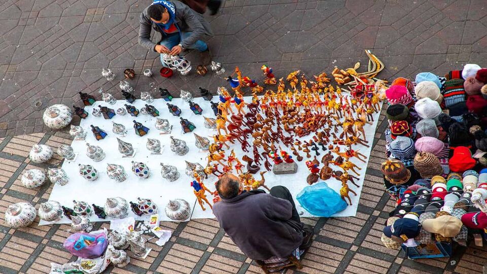 Street seller with various wares (hats, lanterns) laid out on floor