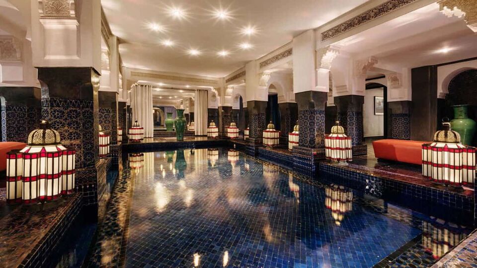 Blue-tiled indoor pool with Moroccan lanterns around the perimeter