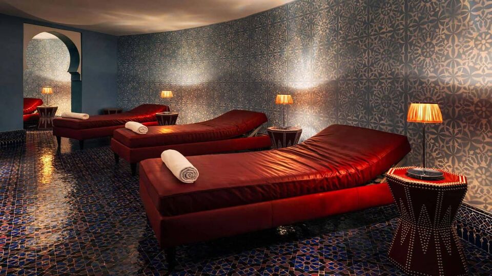 Three red recliner beds in a Turkish Bath, each with their own side table and lamp