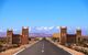 Straight road through the desert with snow-capped mountains in the background