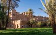 Moroccan castle with lush lawns and palm trees in the foreground