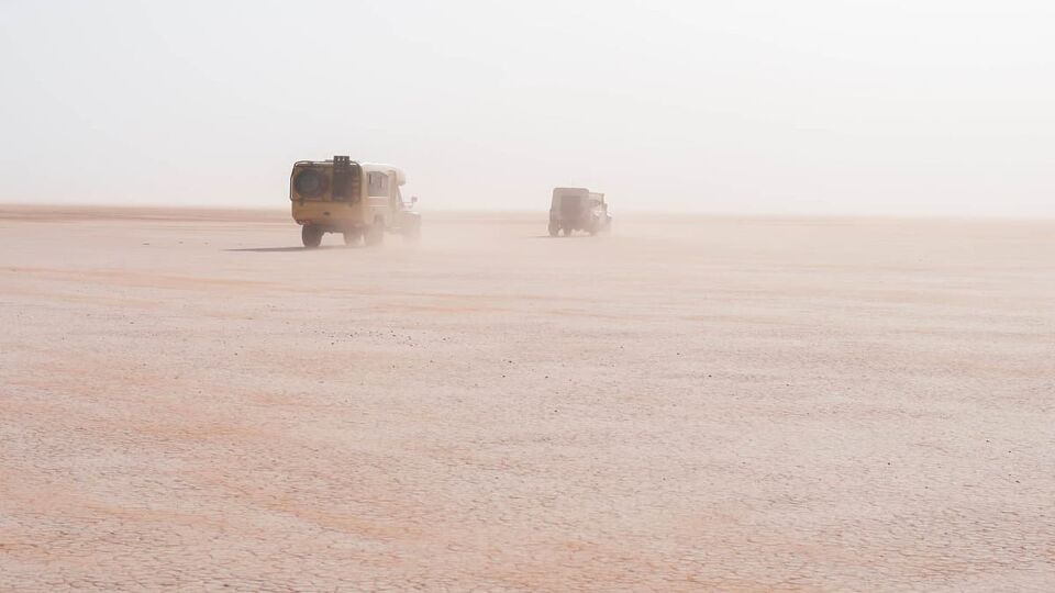 Off-road vehicles drive in a sandstorm