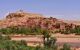 Ancient hilltop town in the desert with river and palm trees in the foreground