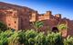 Ancient hilltop town in the desert with palm trees in the foreground