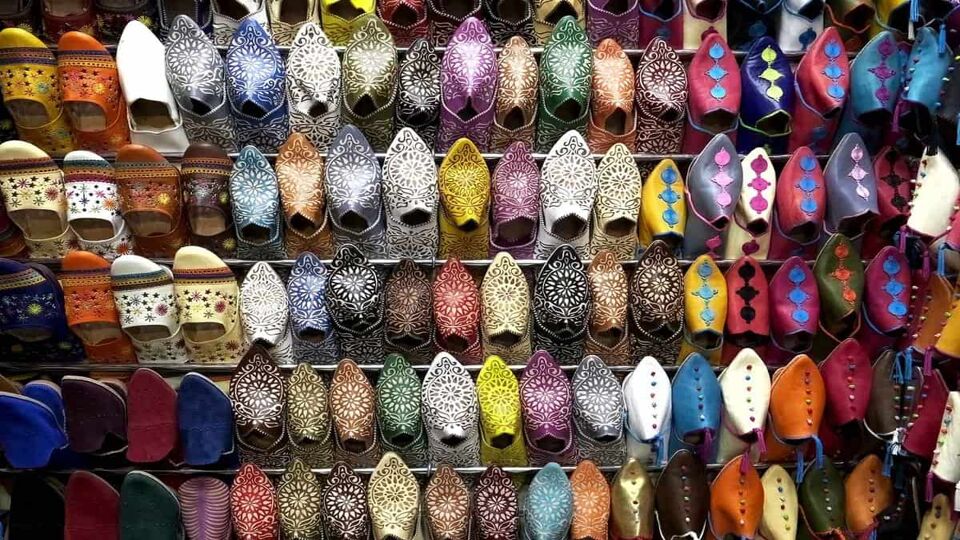 Shop display of colourful leather slippers lining a wall