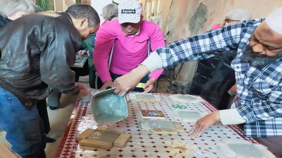 group pouring plaster into moulds to make tiles