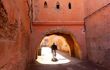 Man on a bicycle passes under a low arch in a narrow street in Marrakech's Medina