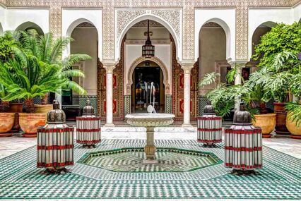 Interior of ornate riad with fountain, plants and tile-work