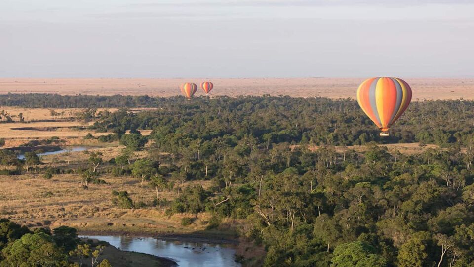 view of several colourful striped hot air balloons floating over the landscape