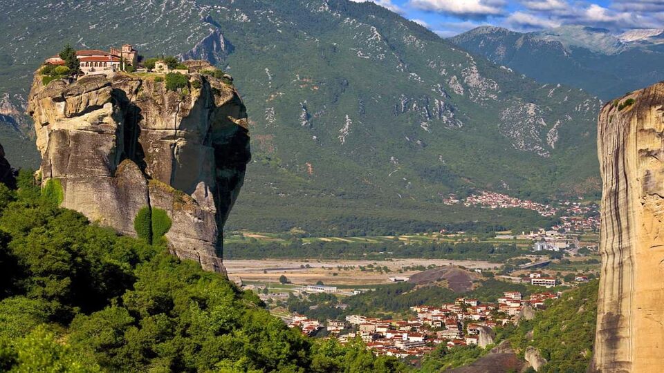 sandstone rock formations rise from the ground and the Monastery of the Holy Trinity on the top of rock