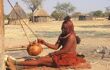 A himba woman sat on the ground crafting something in her hands