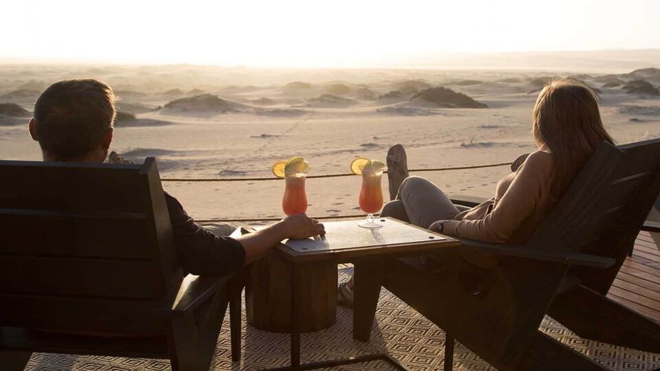 A couple enjoying cocktails facing out to sunset