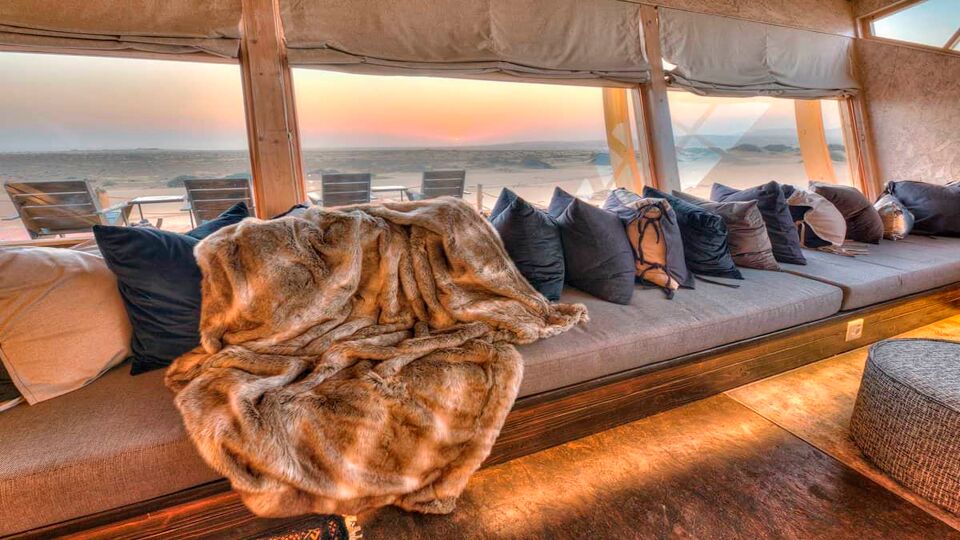 A long sofa looking out across sunset towards the Skeleton coast