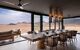 a large dining table with fan and lights above looking out to the desert