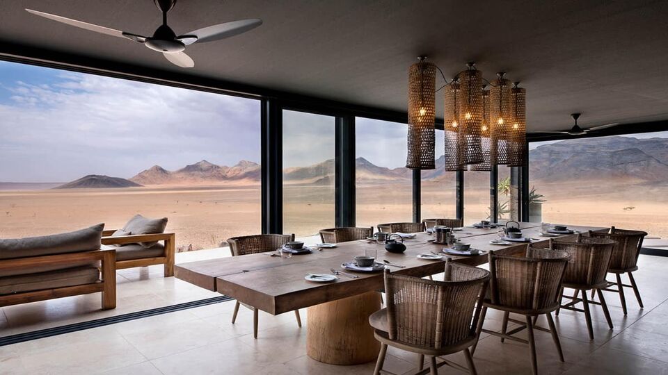 a large dining table with fan and lights above looking out to the desert