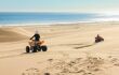 Two people quad biking in the sand desert dunes