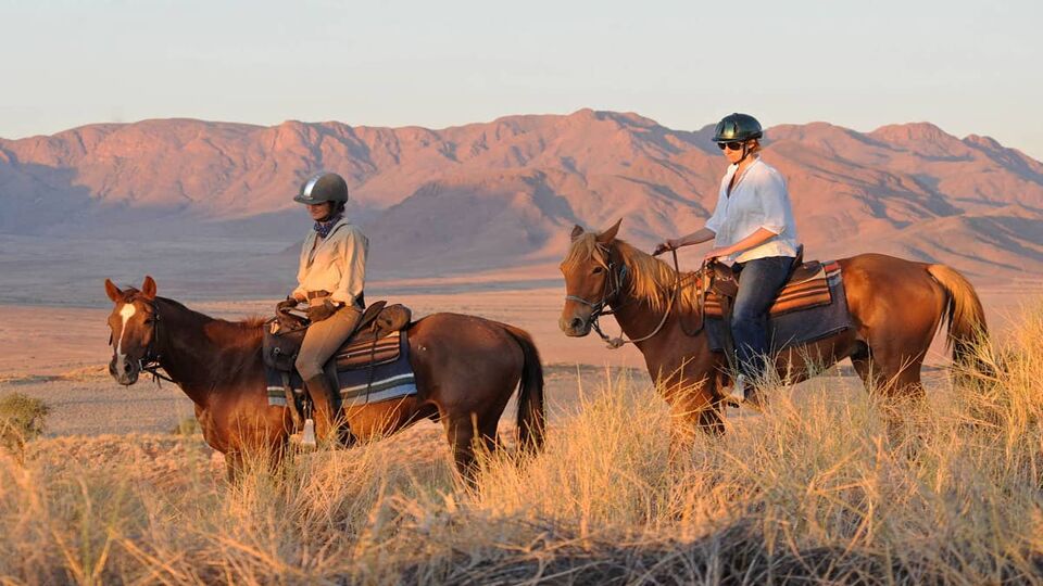two people on horseback riding through the desert