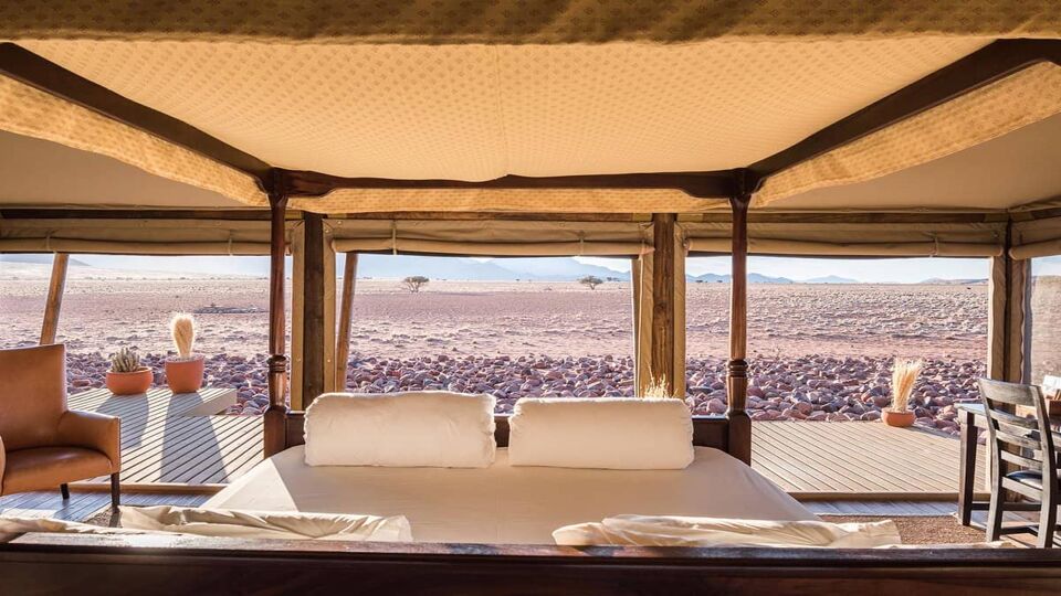 a large double bed in an open room facing the desert