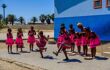 Pretty young girls in beautiful pink costumes perform song and dance routine outside local school