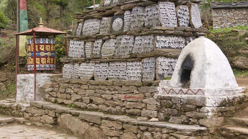 Buddhist Mani stones and prayer wheel along the trekking route to Everest Base camp in Nepal