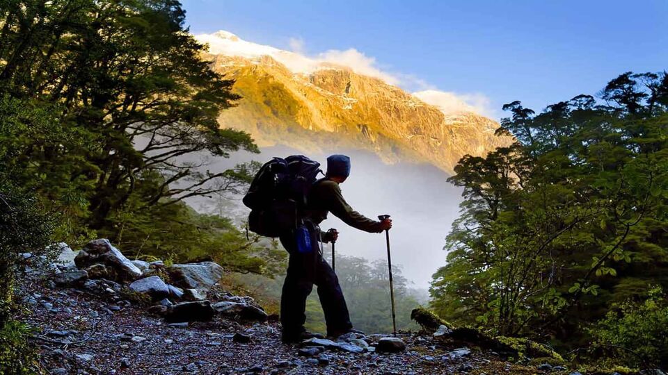 A hiker pauses for a rest at a clearing while ascending into the mountains