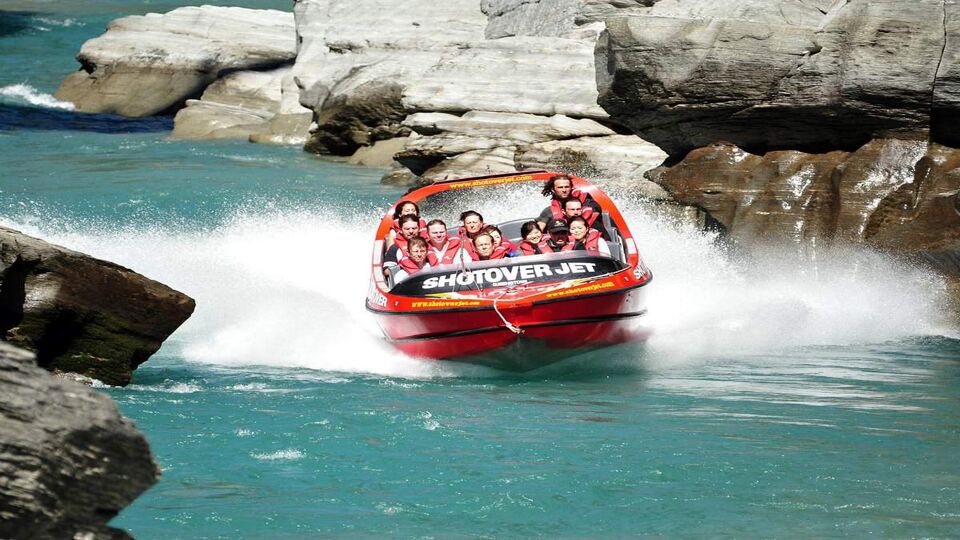 Tourists enjoy a high speed jet boat ride on the Shotover River in Queenstown, New Zealand. Queenstown is one of the most popular summer resort in NZ.