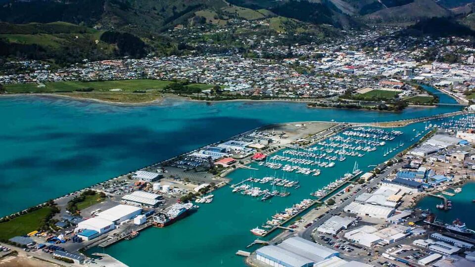 Picton harbor view from above with yachts and ships on turquoise water and rolling hills in the background