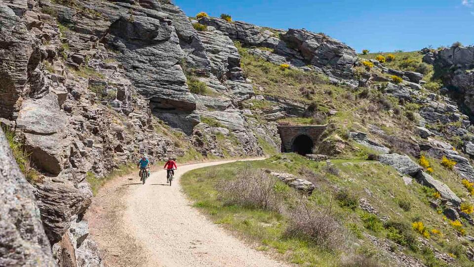 mountain bikers cycling past cliffs on Otago Trail